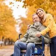 Woman with her elderly father in wheelchair outdoors on autumn day