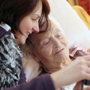 invalid grandmother in latter stages of Parkinson's disease, being cared for at home. Her granddaughter is comforting her with some family photos on a digital camera.